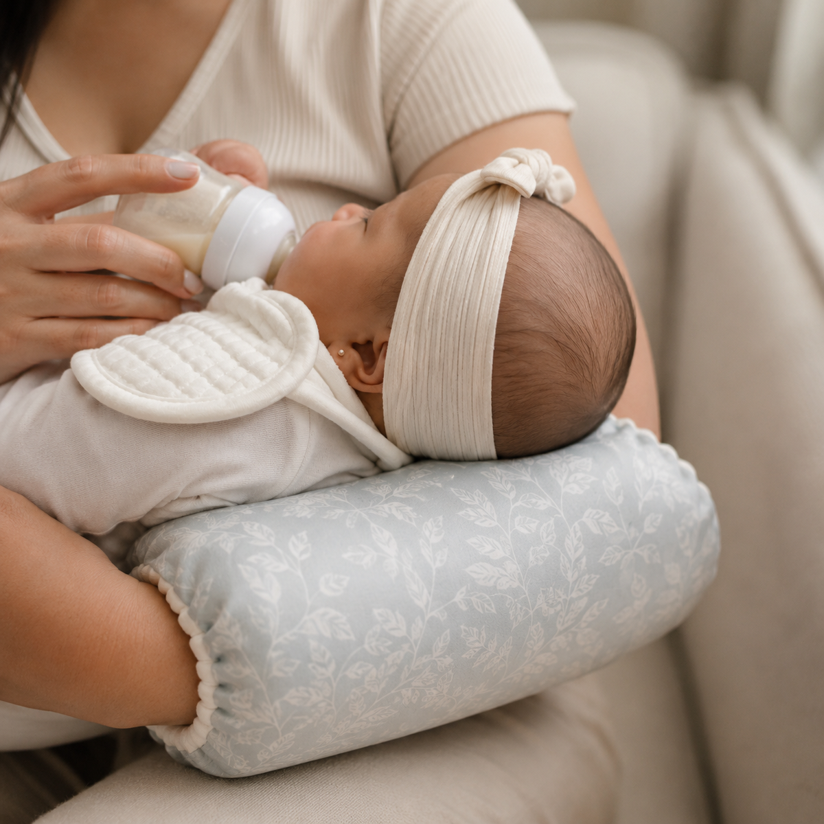 NuriBloom Devora ergonomic baby carrier worn by mother with newborn indoors